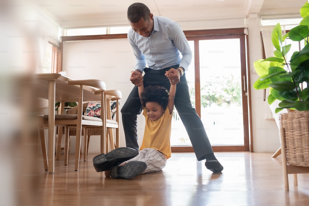 Afroamerikanischer Vater und sein kleiner Sohn spielen zu Hause auf dem Boden.