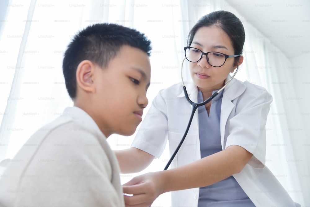 Young Asian Female Doctor examining a little boy with stethoscope. Medicine and health care concept.