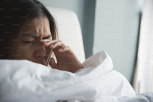Asian woman rubbing eyes with her hand on her bed. Copy space.