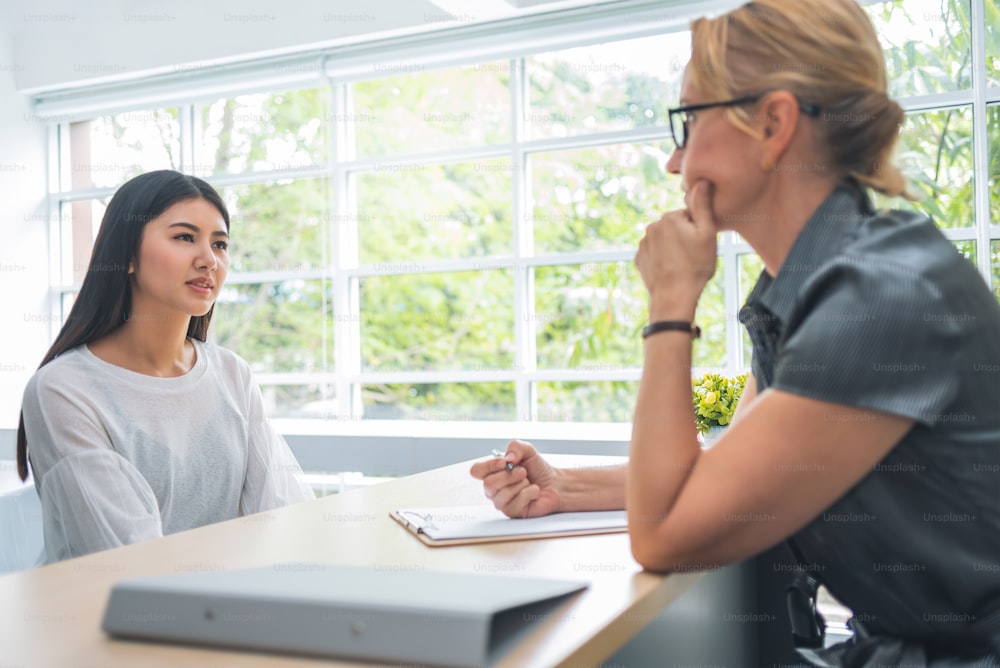 Asian woman talking and listening to senior female during the job interview.