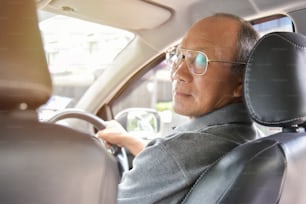 Hombre mayor asiático relajado con gafas conduciendo un automóvil. Concepto de Éxito y Felicidad. Cara sonriente. Jubilación