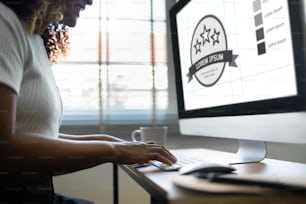 Mulher afro-americana sorridente trabalhando no computador. Designer feminina criativa feliz está fazendo design gráfico enquanto está sentada no estúdio do escritório.