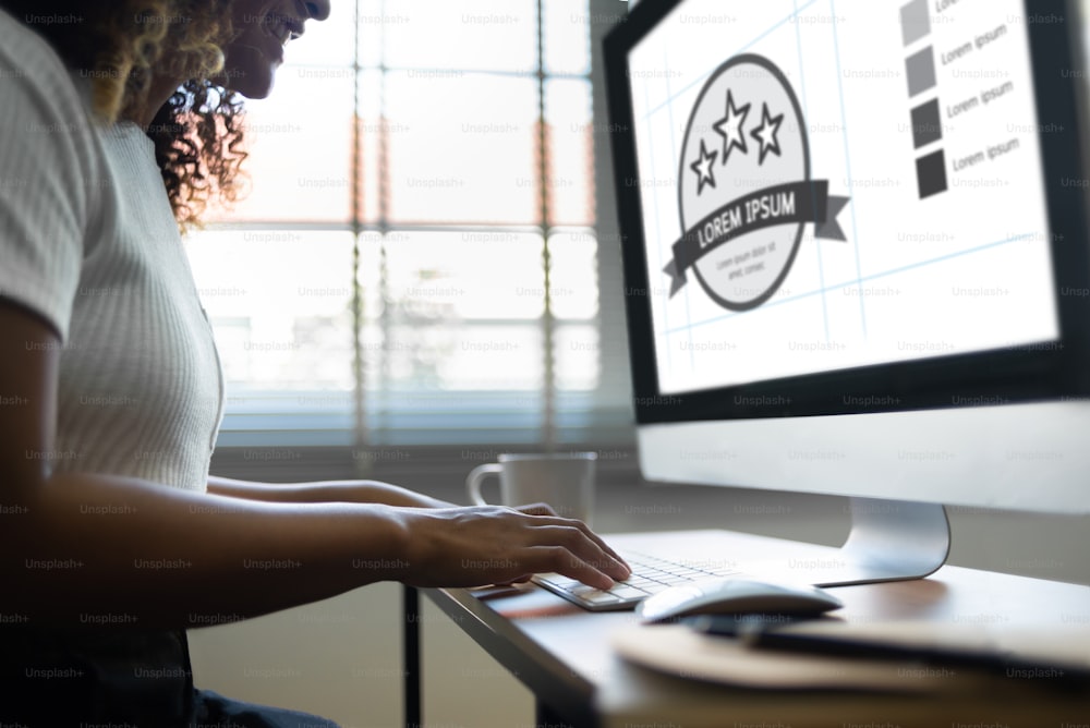 Lächelnde afroamerikanische Frau, die am Computer arbeitet. Glückliche kreative Designerin macht Grafikdesign, während sie im Bürostudio sitzt.