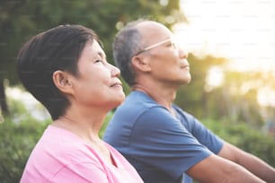 Happy Asian senior couple smiling and breathing fresh air while exercising at park outdoor.