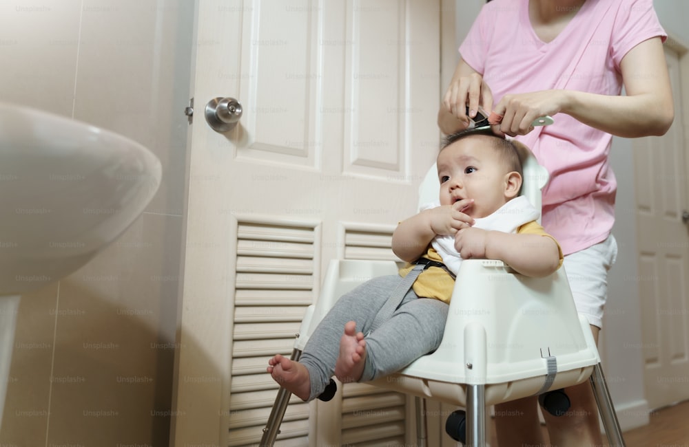 Asian Little baby having haircut with his mother in bathroom at home.