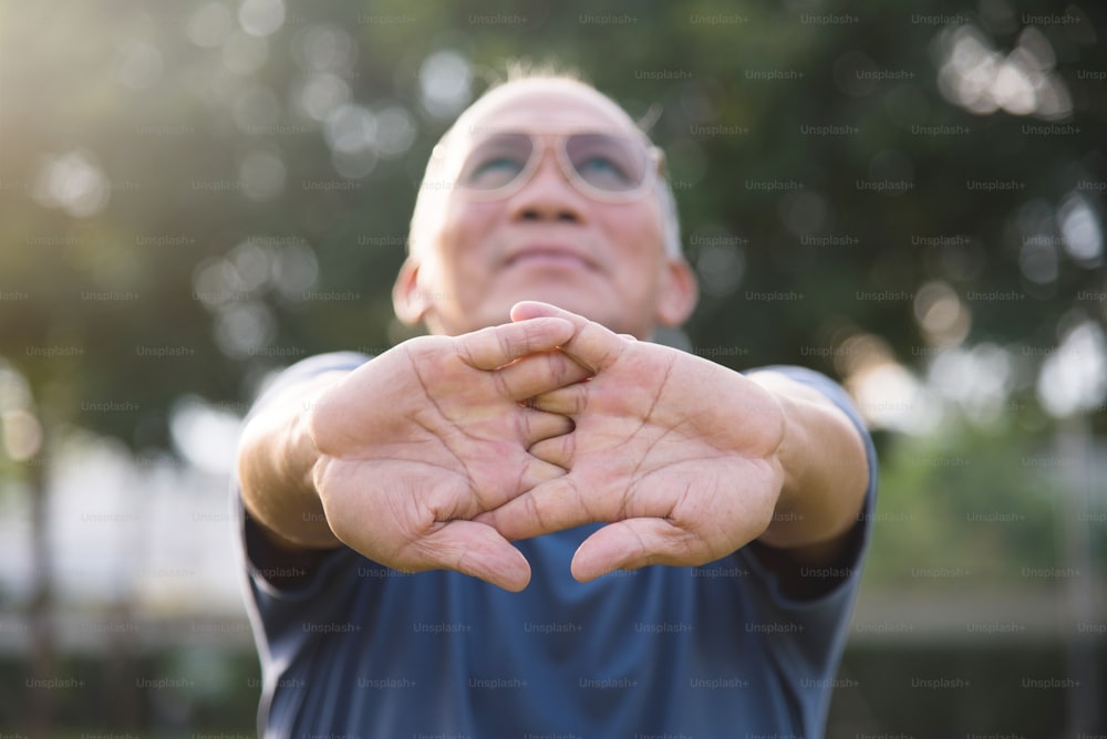 Asian senior male stretching before exercise at park outdoor.