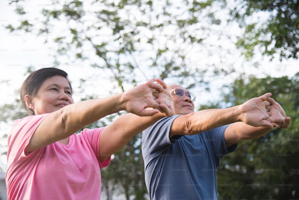 Happy Asian senior couple stretching before exercise at park outdoor.