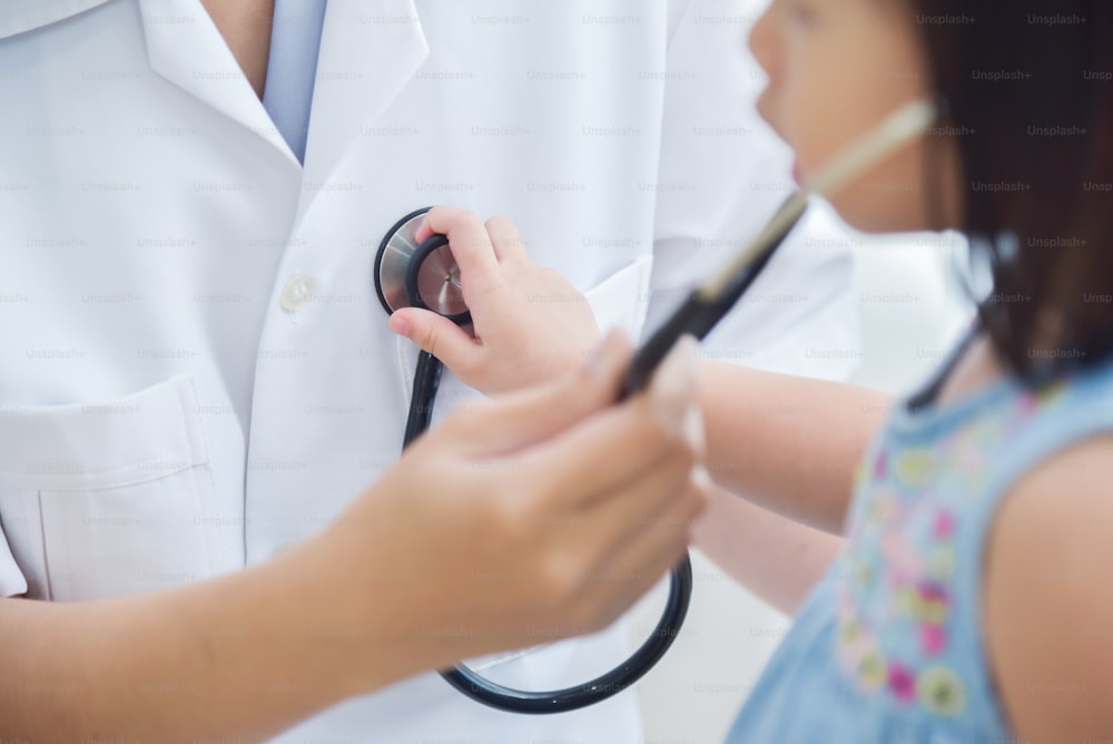 Junge asiatische Ärztin untersucht ein kleines Mädchen. Stethoskop. Medizin und Gesundheitskonzept.