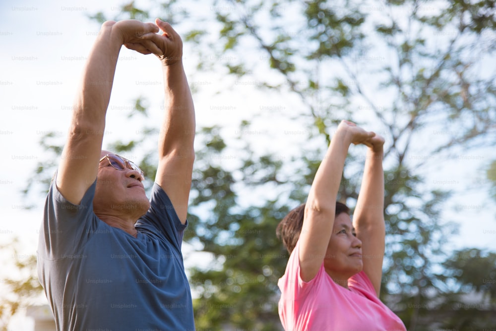 Heureux couple de personnes âgées asiatiques s’étirant avant de faire de l’exercice au parc en plein air.