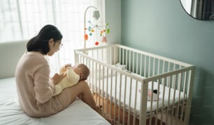 Young mother and Adorable infant baby boy playing on bed together. Happy Asian mom her Cute son and in bedroom.