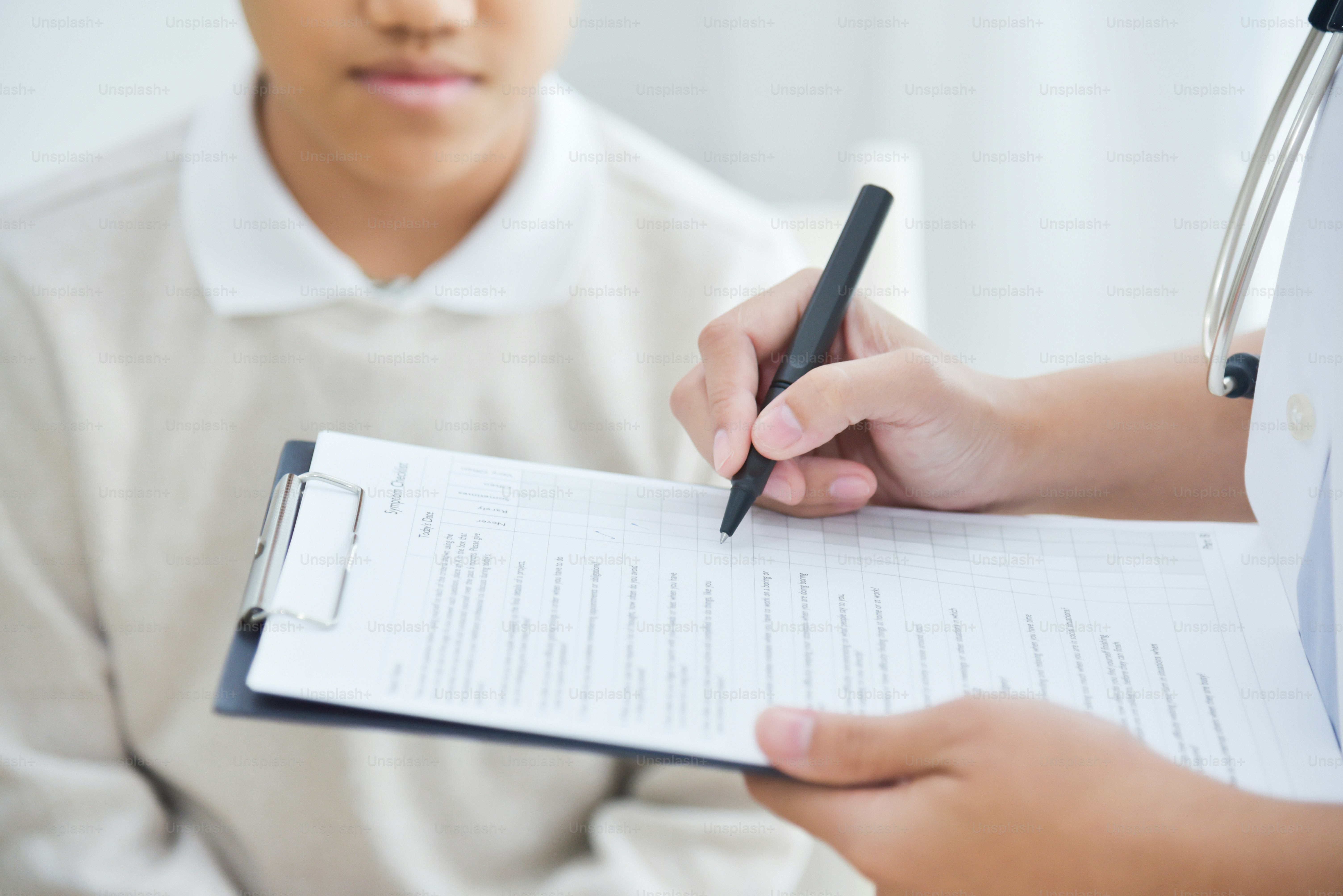 Asiatische Ärztin notiert sich Checkliste für kleine Jungenpatienten.