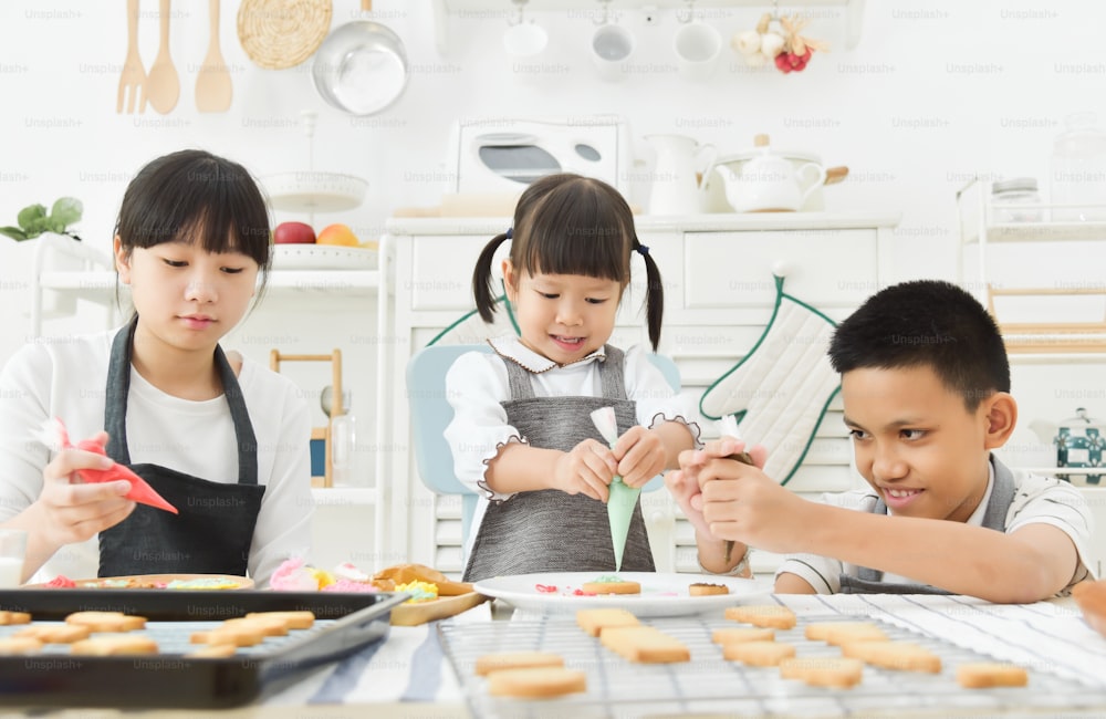 Asian Kids decorating cookies in the kitchen.