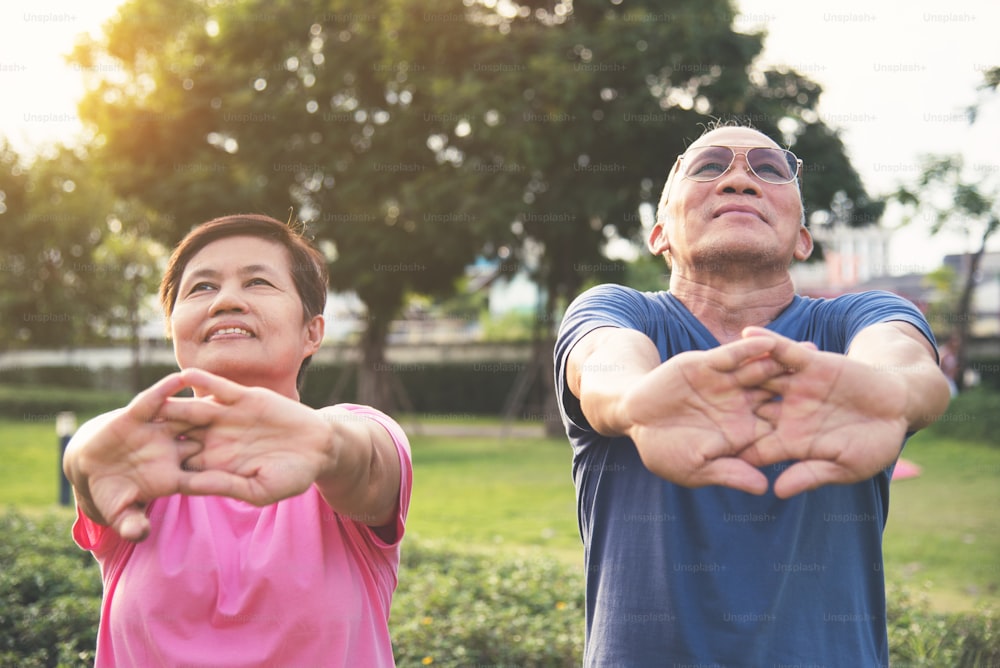 Des personnes âgées asiatiques heureuses qui s’étirent avant de faire de l’exercice dans un parc en plein air.