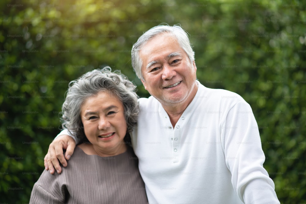 Retrato do casal sênior asiático sorrindo e olhando para a câmera no parque. Idosos felizes com sentimento positivo ao ar livre. Aposentadoria.