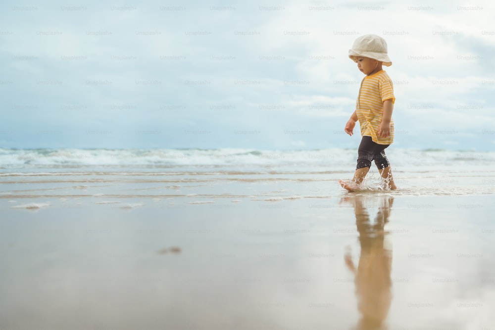 Asian boy walking on the beach. Adorable child in outdoor summer holiday vacation