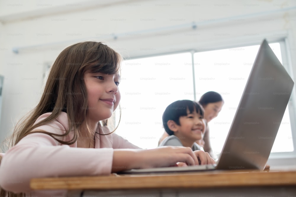 Felice ragazza carina sorridente che usa il laptop mentre studia in classe alla scuola internazionale. Istruzione ed E-Learning con la tecnologia