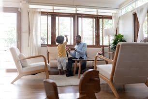 African American Dad playing and having fun with his little son on the couch of living room at home. Happy Black family. Single father