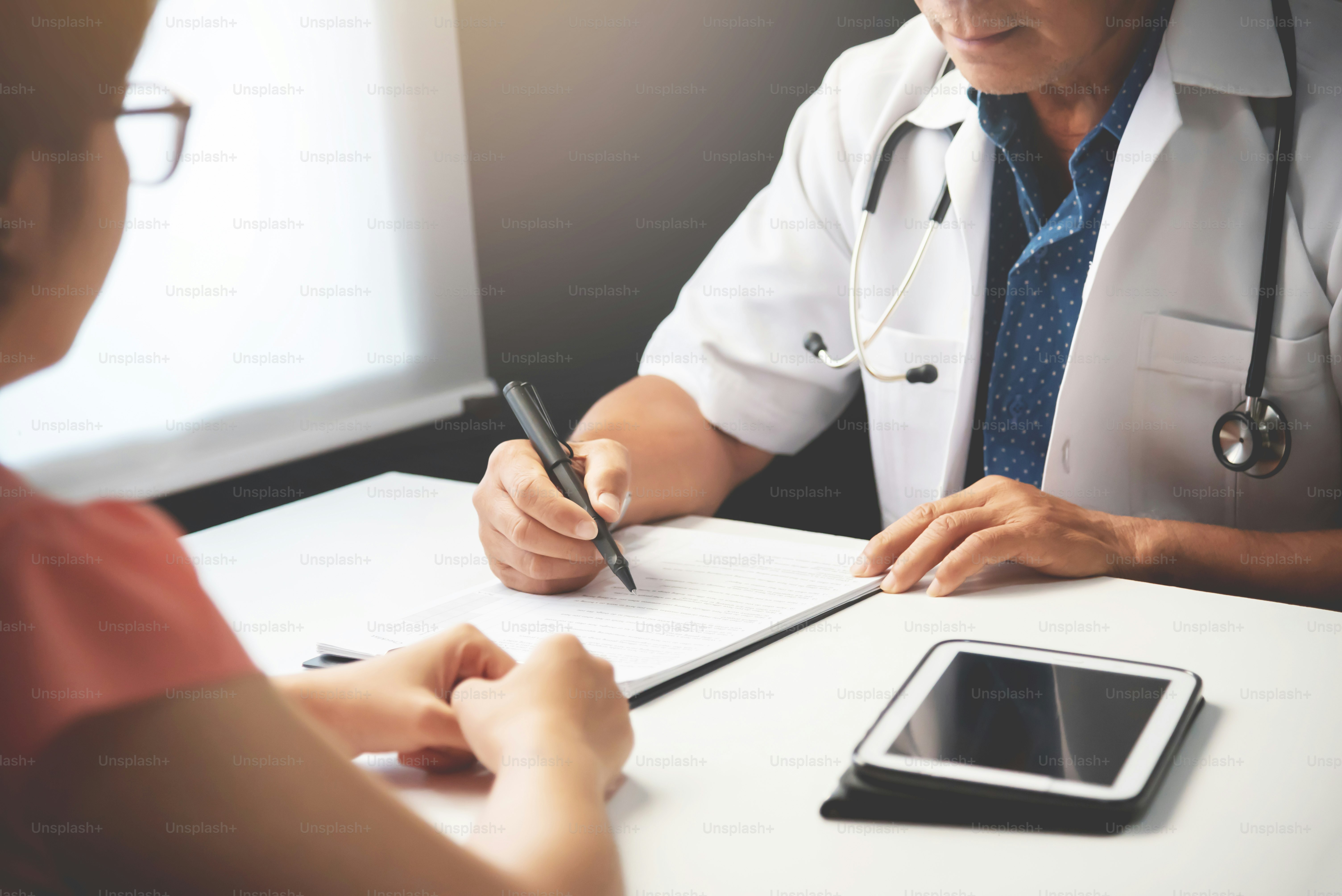 Asian Senior male Doctor discussing with Female patient in medical room.