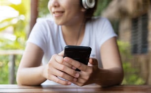 Happy Asian Woman listening to the music with headphone and smart phone at outdoor. Having fun. Relaxed.