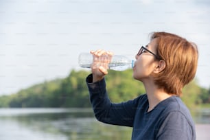 Mujer asiática viajera bebiendo agua en fondo natural.