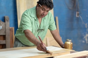 Mexican woodworker, carpenter varnishing on his workshop