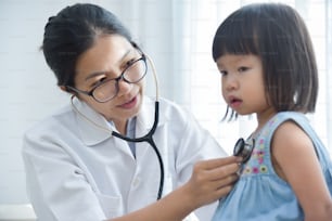 Young Asian Female Doctor examining a little girl with stethoscope. Medicine and health care concept.