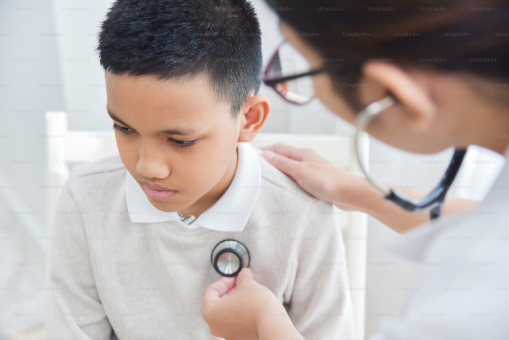 聴診器で小さな男の子を診察する若いアジアの女性医師。医学とヘルスケアのコンセプト。