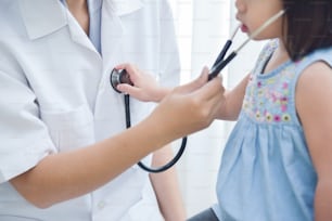 Junge asiatische Ärztin untersucht ein kleines Mädchen. Stethoskop. Medizin und Gesundheitskonzept.