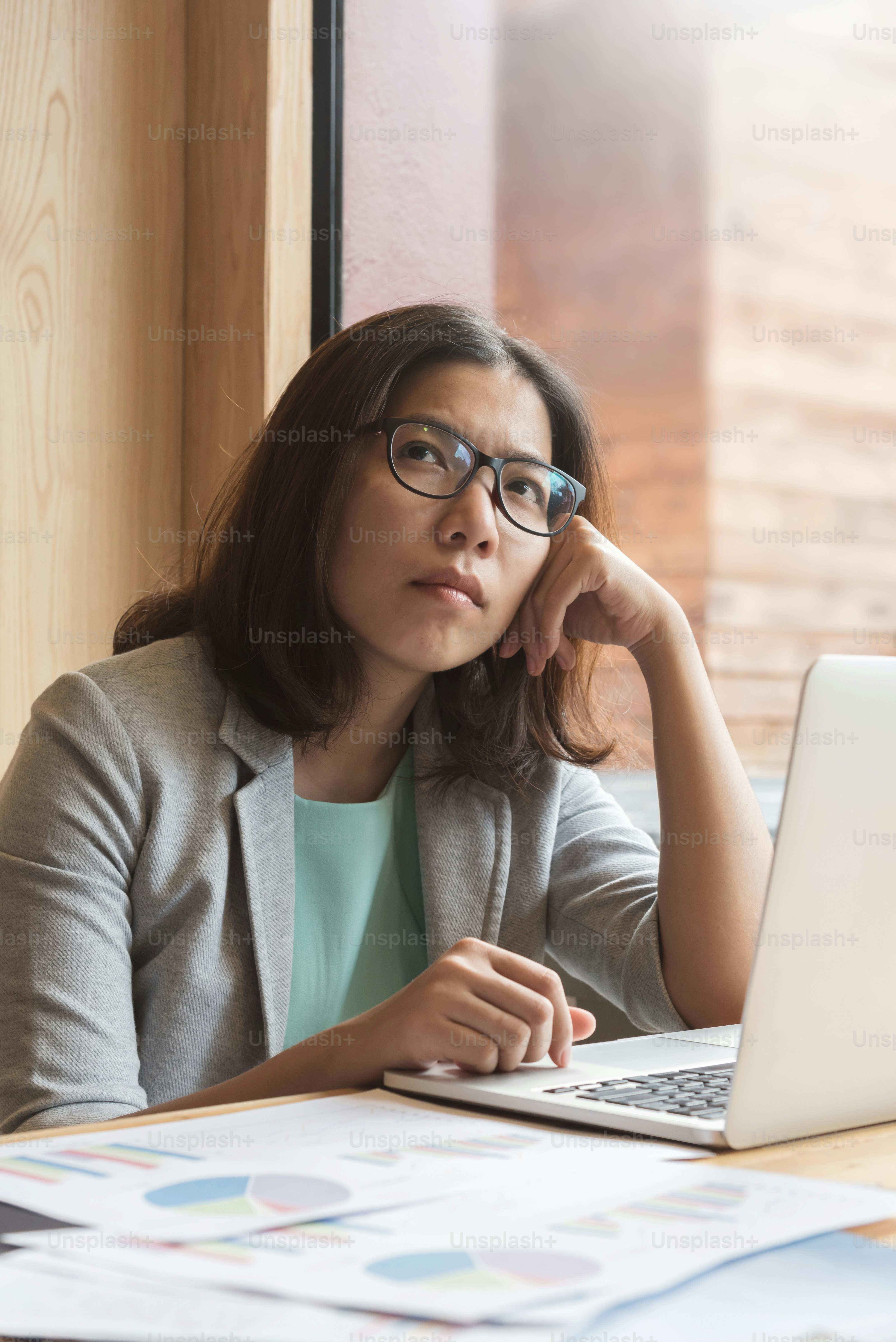 Femme d’affaires asiatique avec un ordinateur portable pensant à son travail sur son lieu de travail.