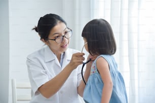 Jovem Médica Asiática examinando uma garotinha com estetoscópio. Conceito de medicina e saúde.