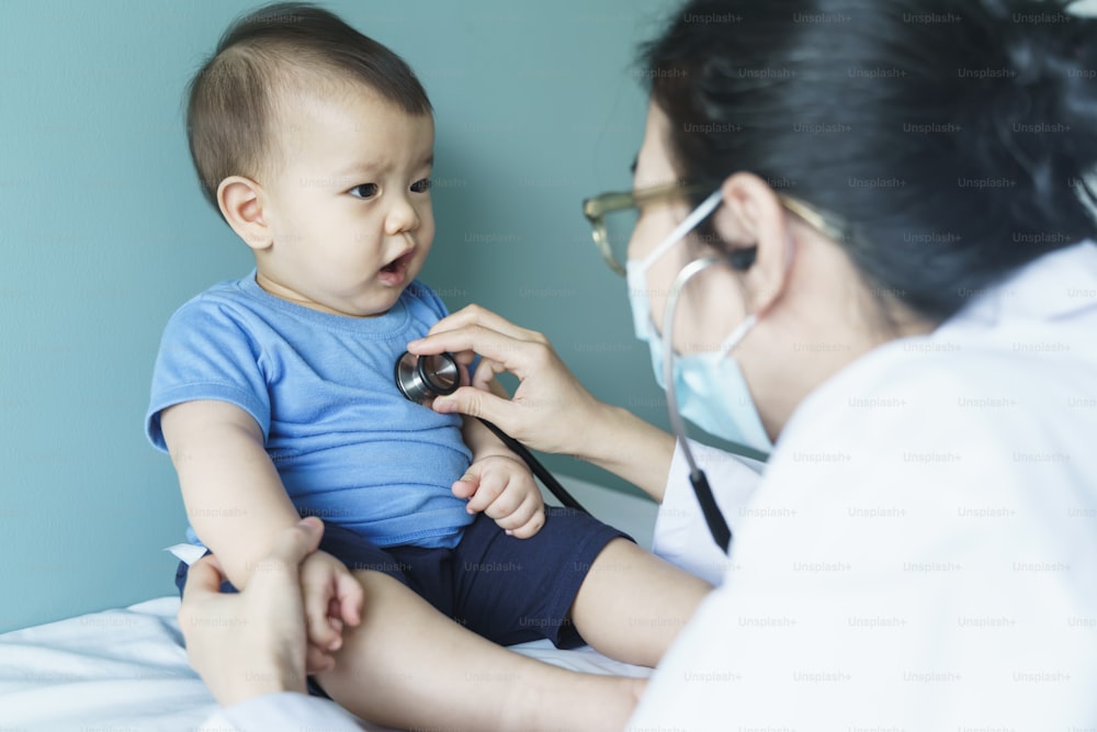 Asiatische Ärztin verwendet Stethoskop zur Überprüfung von Herzschlag und Lunge mit Patient Baby Junge, Medizinische Untersuchung