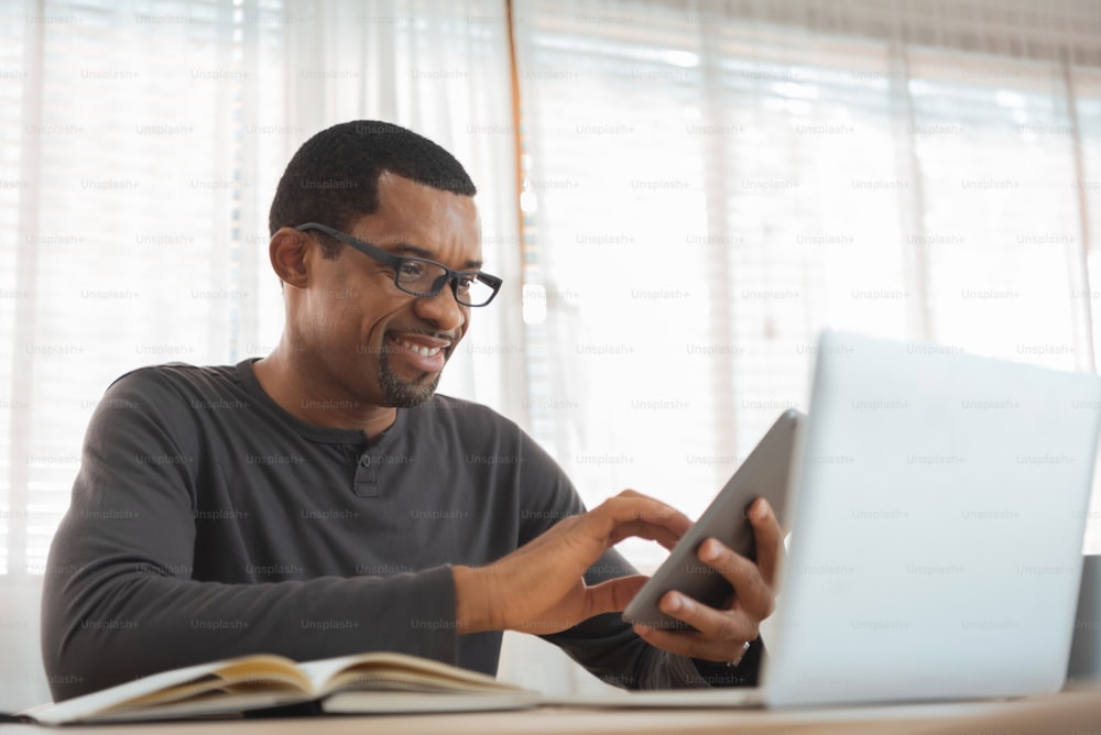 African American Freelancer male using digital tablet and laptop computer, Working at home.