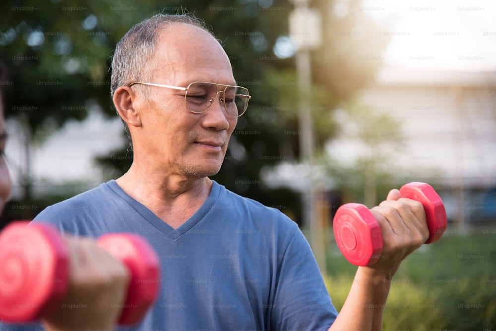 Happy Asian Senior people exercising with lifting dumbbell at park outdoor together.