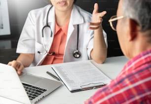 Young Asian Female Doctor consulting with senior man patient in medical room.