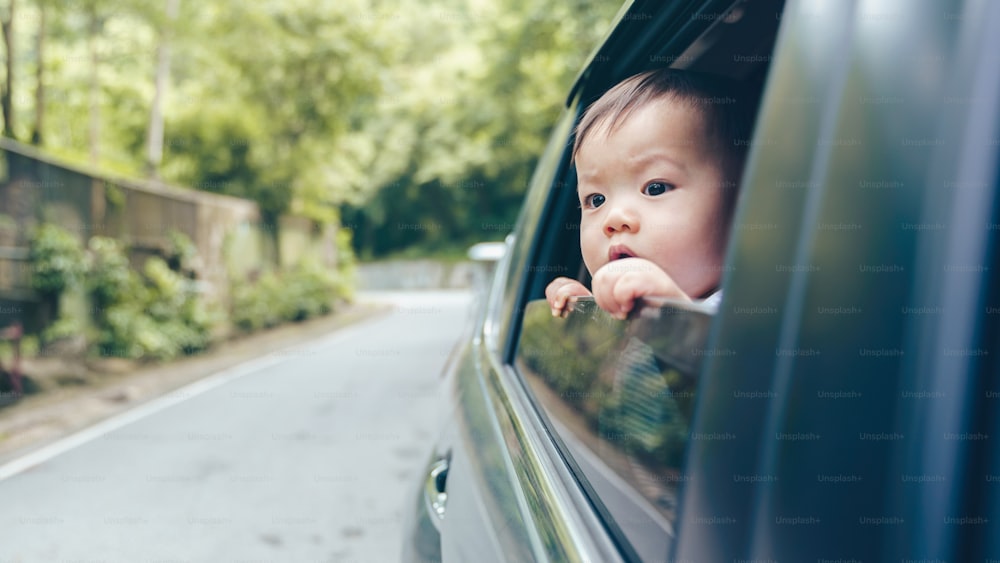 Asian little boy looking out of the window car while having a road trip with family, Transportation and travel, Summer vacation
