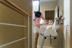 Asian Little toddler boy getting haircut by his mother with electric razor in bathroom at home.