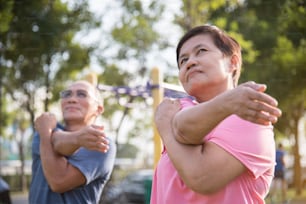 Asian senior couple stretching before exercise at park outdoor.