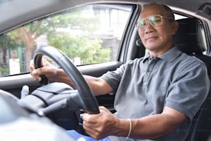 Hombre mayor asiático relajado con gafas conduciendo un automóvil. Concepto de Éxito y Felicidad. Cara sonriente. Jubilación