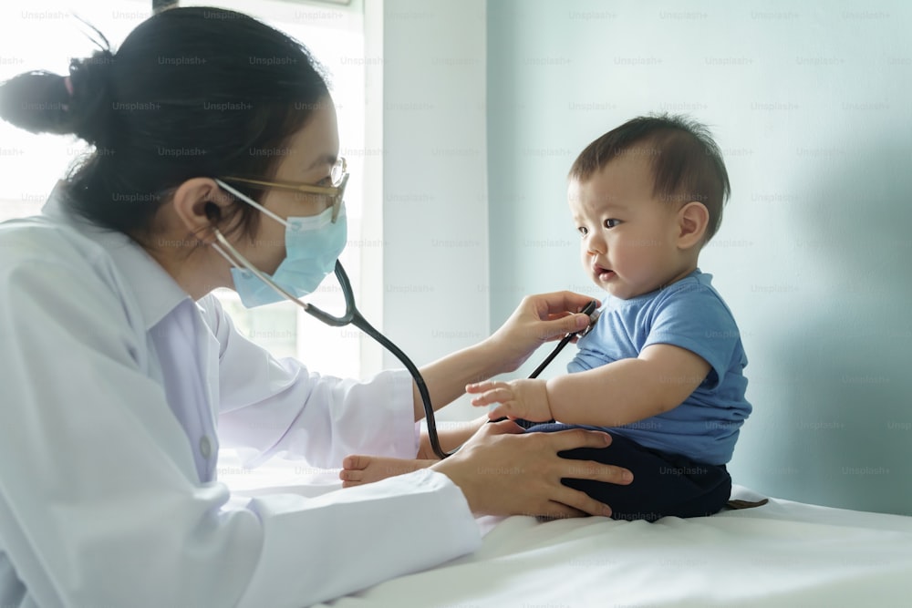 아시아 여성 의사는 청진기를 사용하여 병원의 의료실에서 작은 아기를 검사하고 의료 건강 검진 개념.