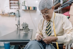 Sastre mexicano envejecido cosiendo a mano en negocio local