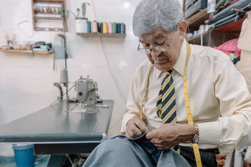 Aged Mexican tailor sewing by hand on local business