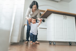 Asiatische Mutter spielt mit ihrem kleinen Sohn in der Küche zu Hause