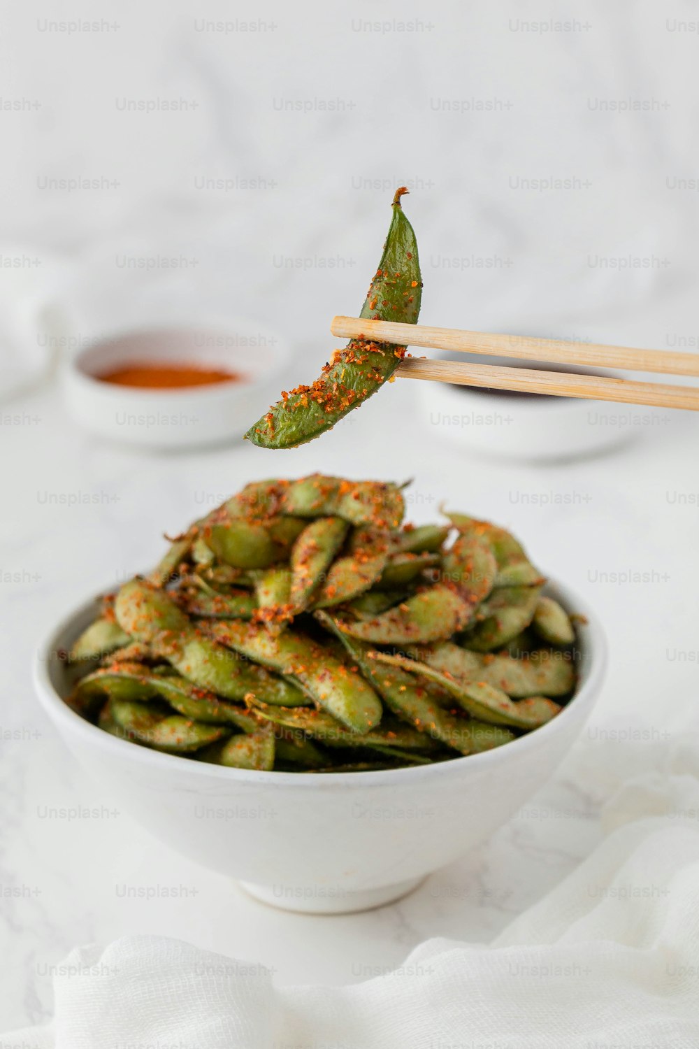 a white bowl filled with green beans and chopsticks