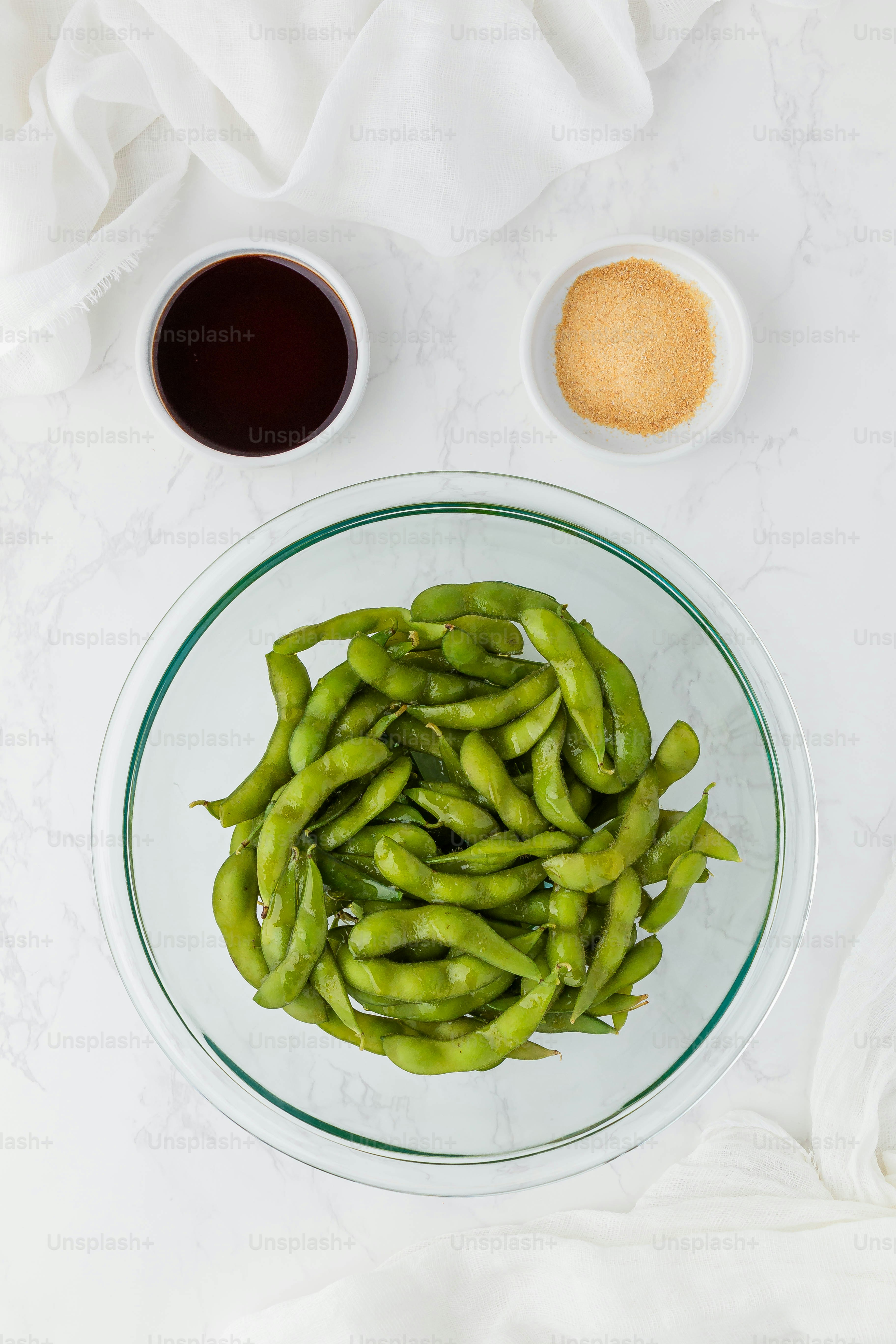 une assiette de haricots verts à côté d’un bol de sauce