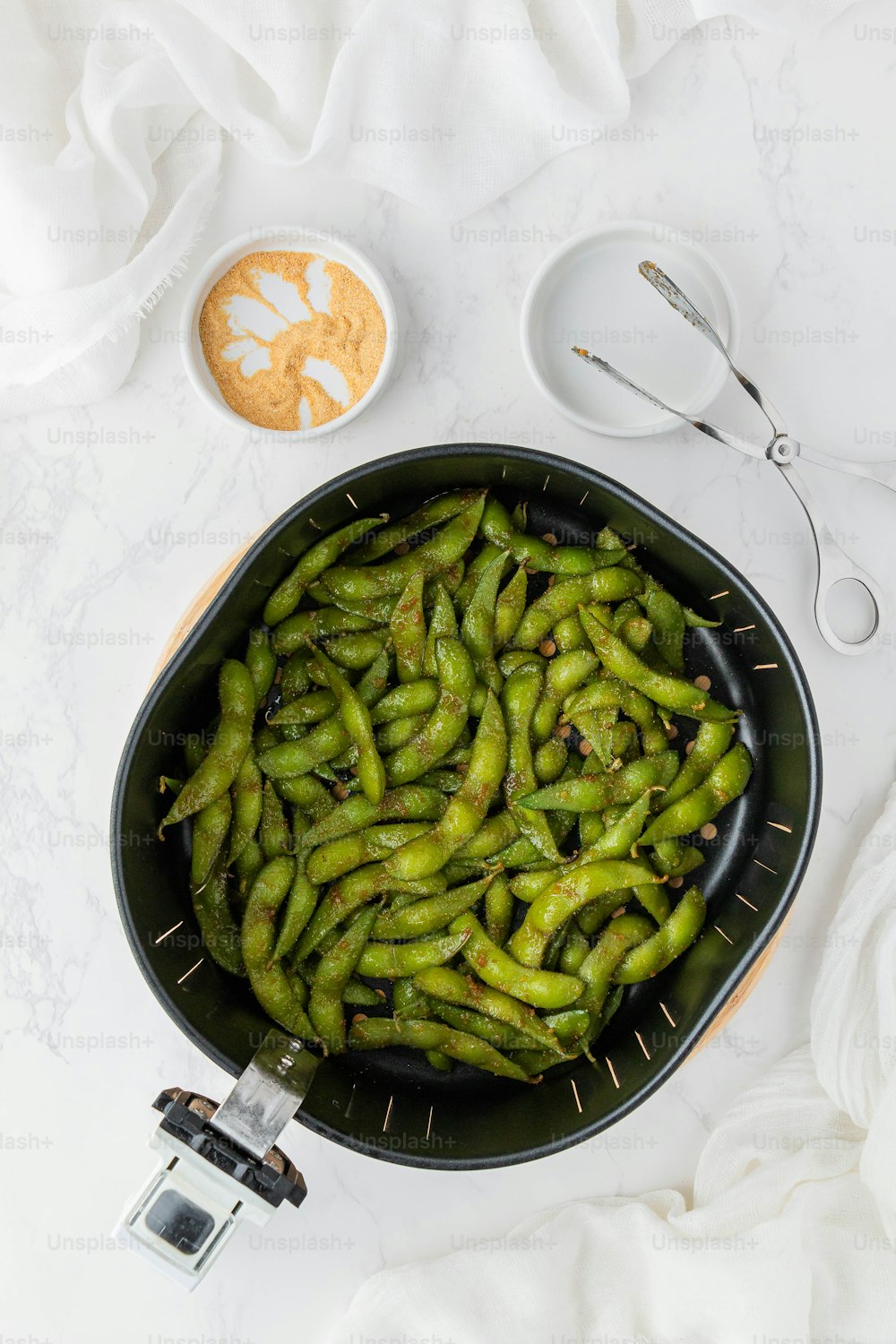 a black bowl filled with green beans next to a camera