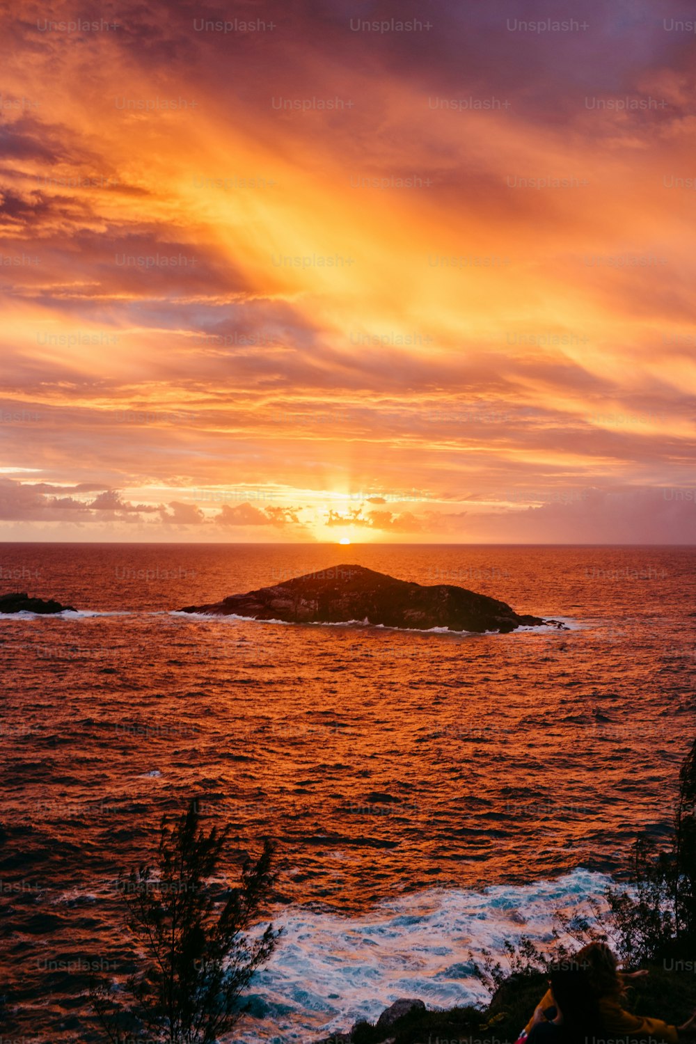 a sunset over a body of water with a small island in the distance