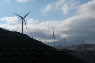 Un grupo de molinos de viento en una colina bajo un cielo nublado