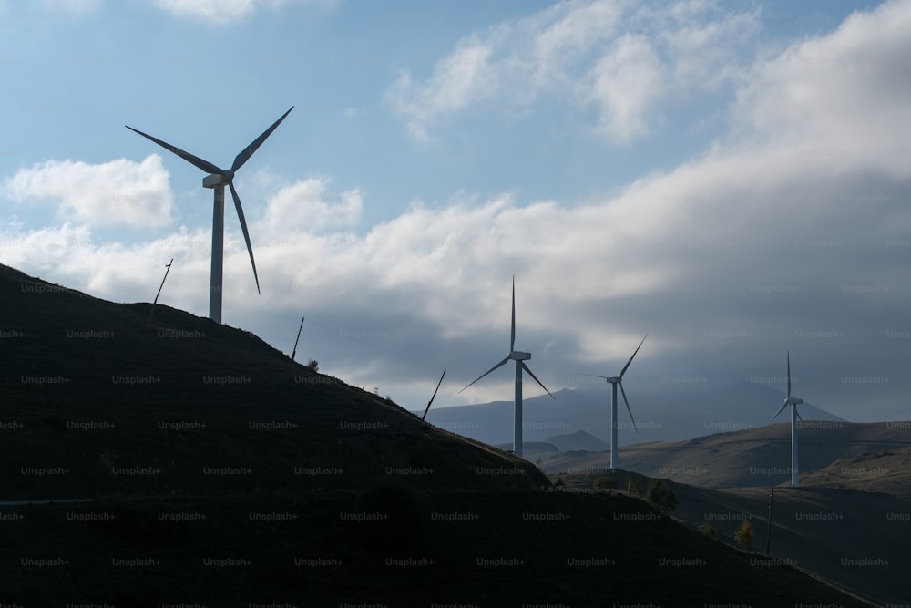 a group of windmills on a hill under a cloudy sky
