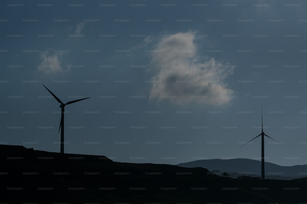 Un par de molinos de viento que están en una colina