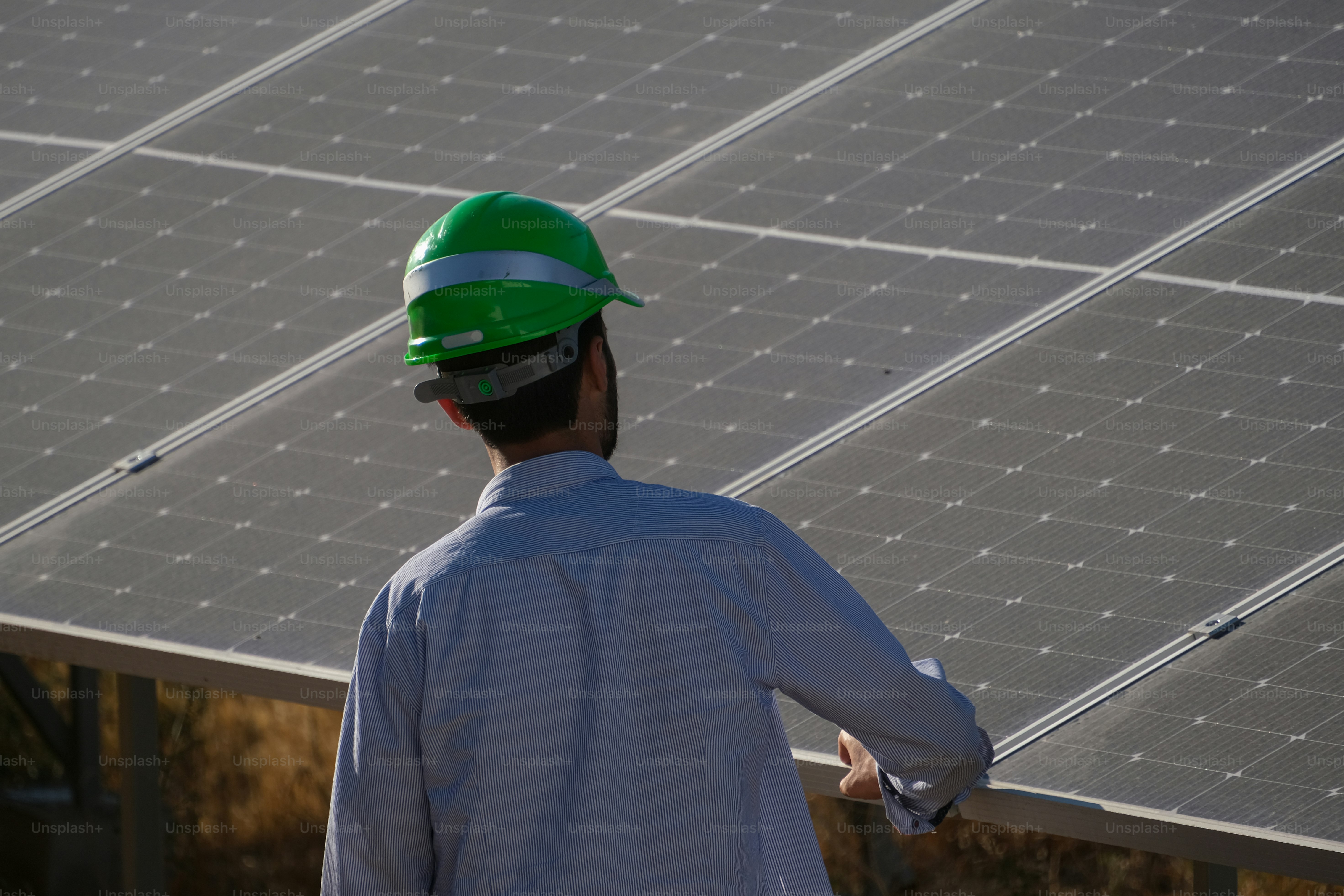 a man wearing a hard hat standing in front of a solar panel